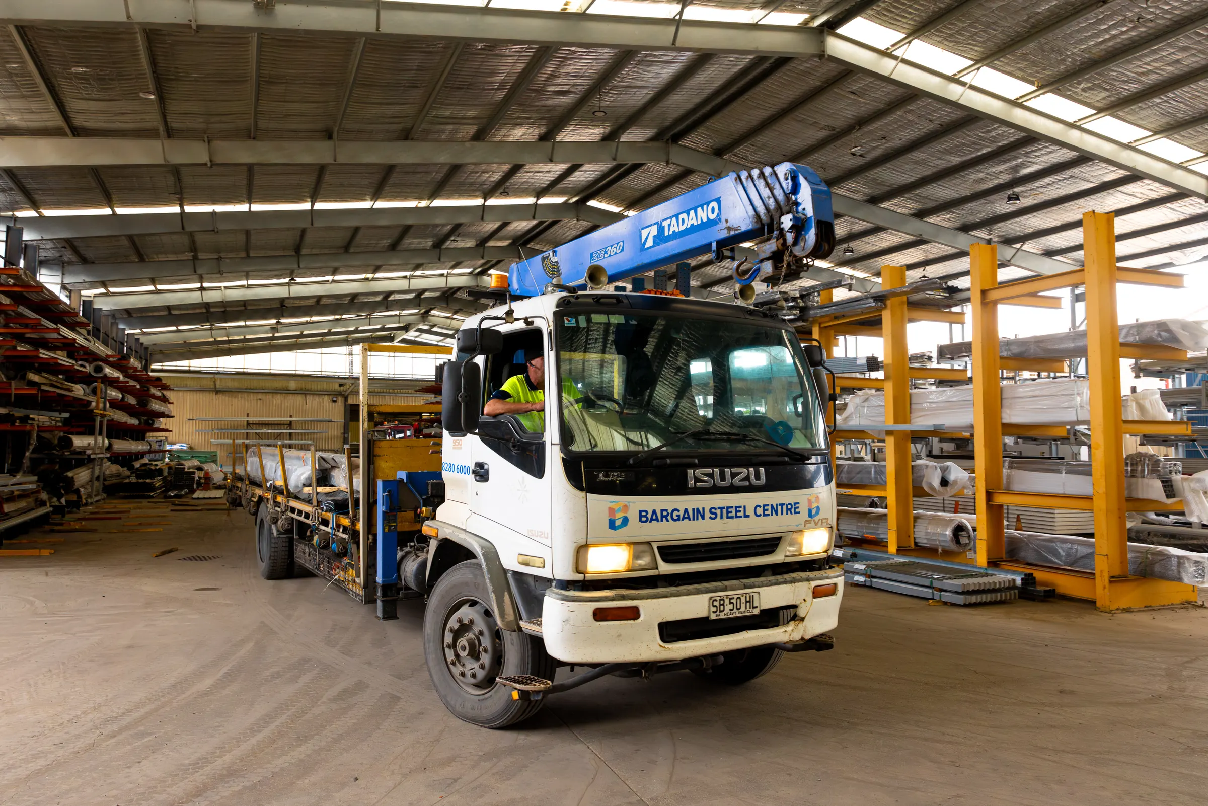 Crane-fitted delivery truck loading in the warehouse